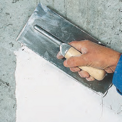 Fehér kültéri simítóglett felhordása beton falfelületre glettvassal.